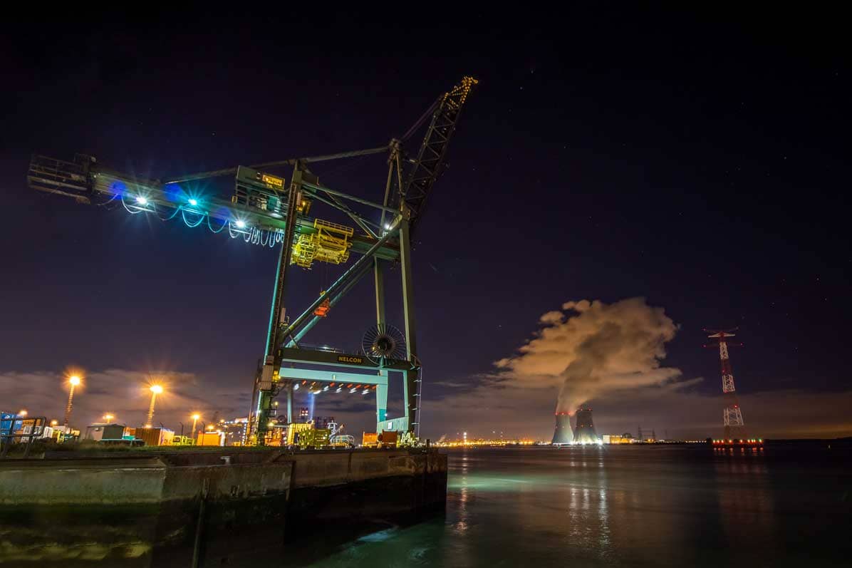 Massieve havenkraan in de Haven van Antwerpen met koeltorens Doel