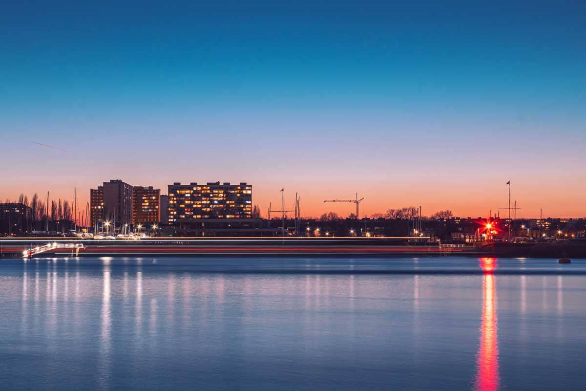 Long exposure van waterbus op de Schelde tijdens zonsondergang met skyline van Linkeroever Antwerpen