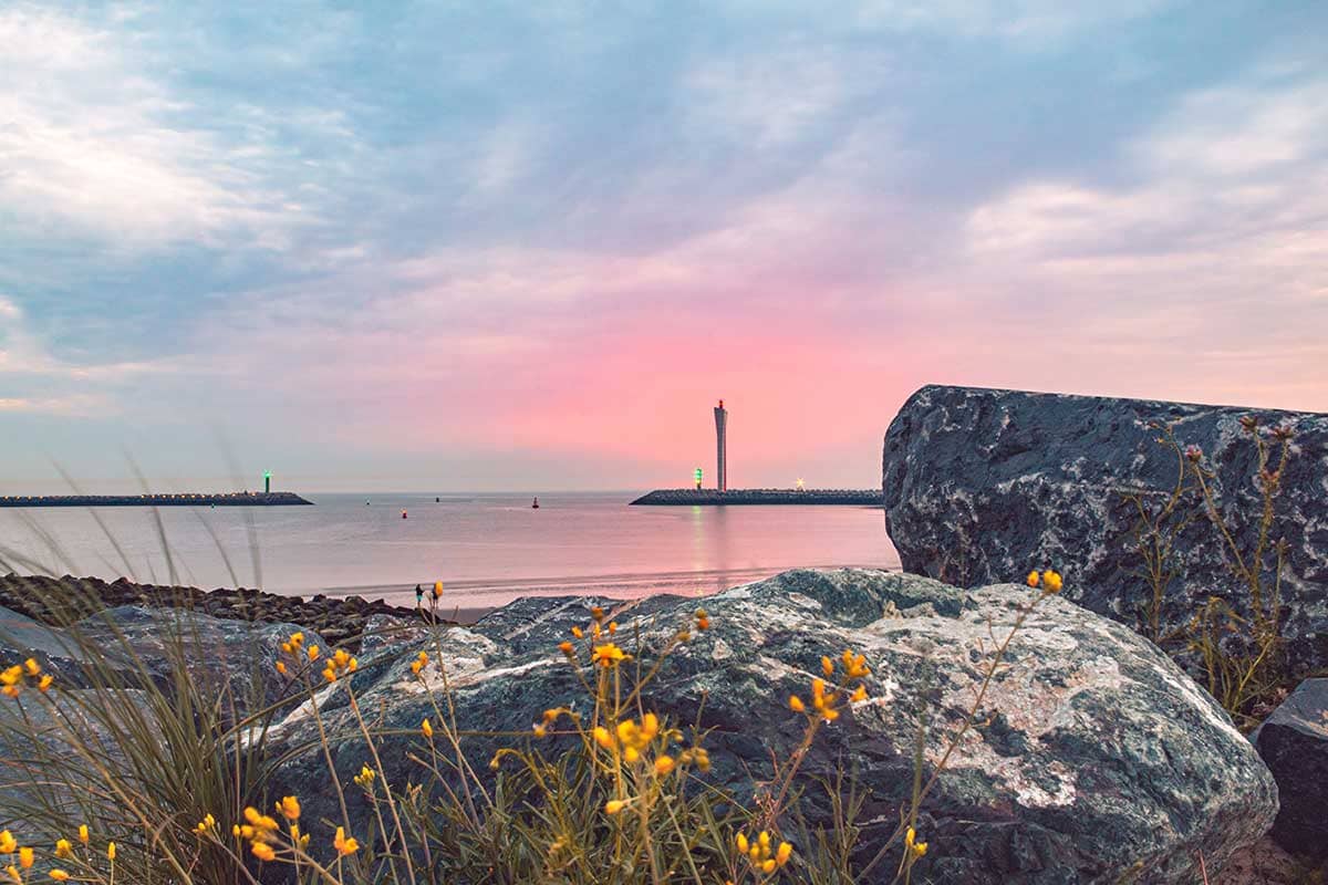 Pastelkleurige zonsondergang met rotsen op voorgrond aan Oostende Oosteroever