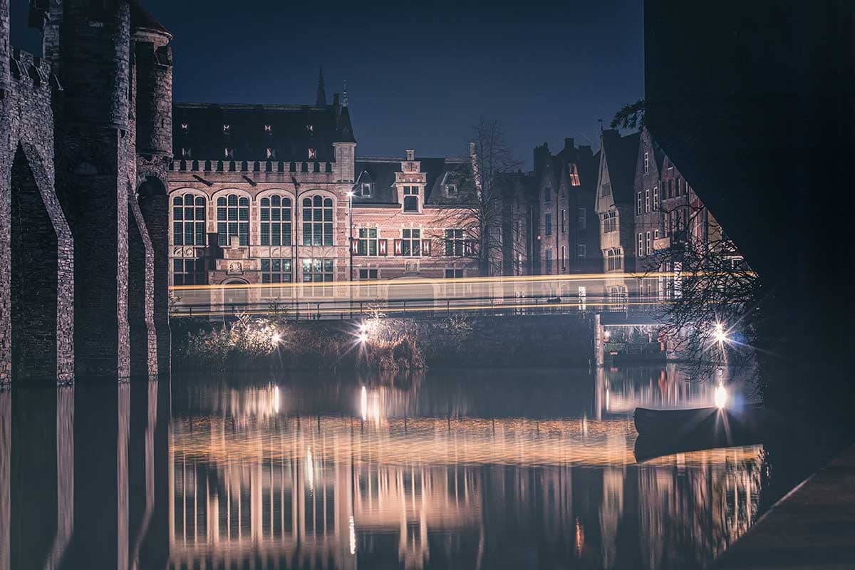 Nachtopname van de Middeleeuwse huisjes met voorbijrijdende tram bij het Gravensteen in Gent