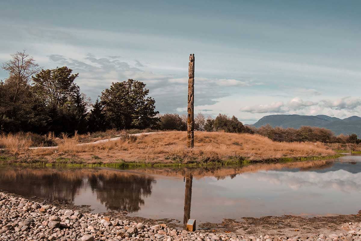 Totempaal weerspiegeld in meer in Vancouver, Canada